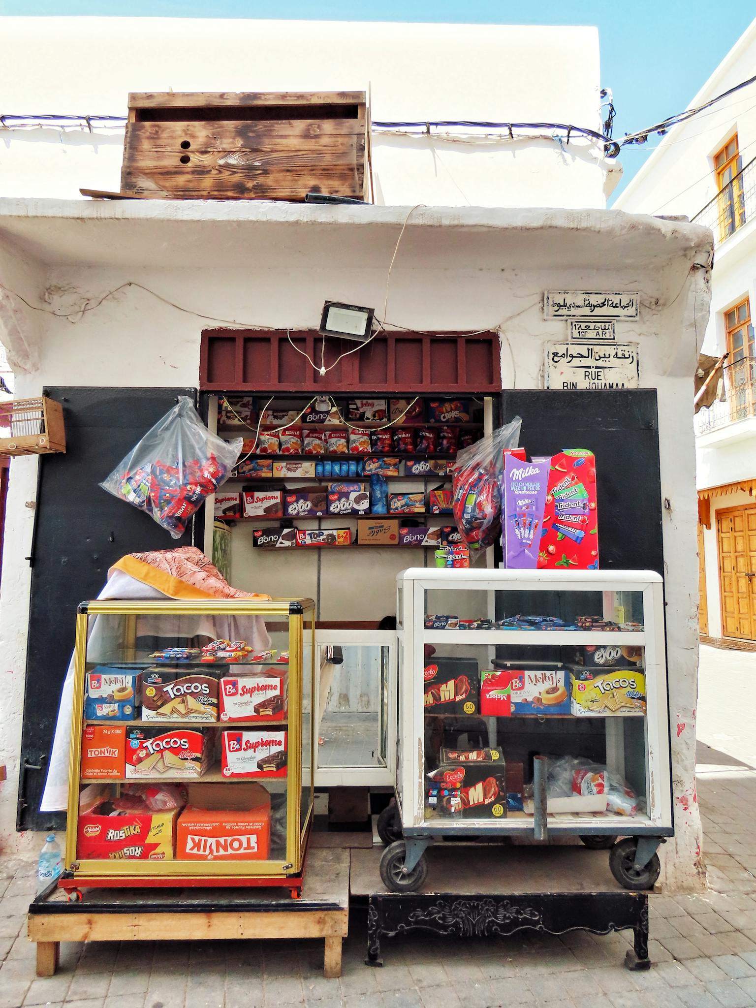 A nostalgic look at a traditional Moroccan street stall selling sweets and snacks in an old town.